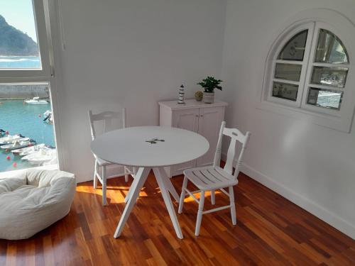 una mesa y sillas blancas en una habitación con ventana en Atsedenportua, en Arminza