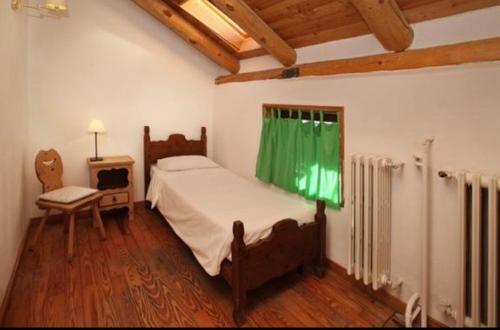 a bedroom with a bed and a chair and a window at Hotel Derby Bar in Sauze dʼOulx