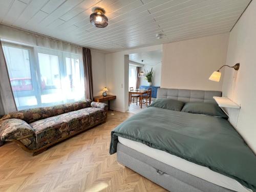 a bedroom with a large bed and a couch at Apartment Entenbrücke in Wendlingen am Neckar