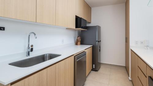 a kitchen with a sink and a refrigerator at Brand New Condo Aria Ocean 501 by Kivoya in Nuevo Vallarta 