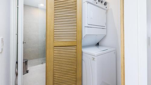 a bathroom with a washer and dryer next to a refrigerator at Brand New Condo Aria Ocean 501 by Kivoya in Nuevo Vallarta 