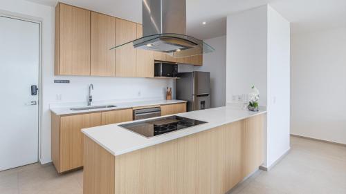 a kitchen with wooden cabinets and white counter tops at Brand New Condo Aria Ocean 501 by Kivoya in Nuevo Vallarta 