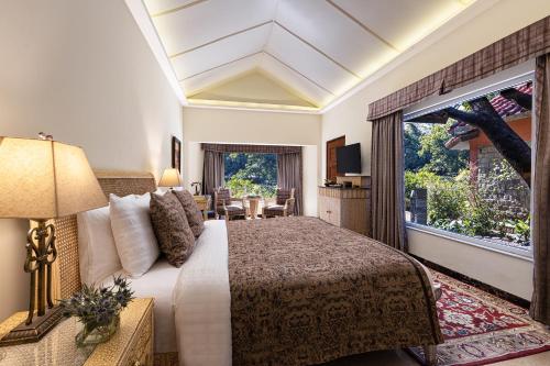 a hotel room with a bed and a large window at Taj Corbett Resort and Spa Uttarakhand in Rāmnagar