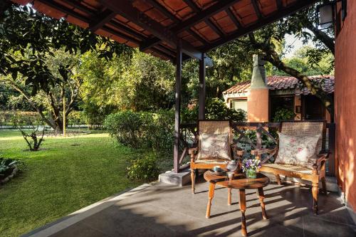 a patio with two chairs and a table and a house at Taj Corbett Resort and Spa Uttarakhand in Rāmnagar