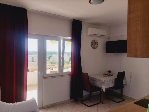 a living room with a table and a window at Apartments Donadic II, Caska in Novalja