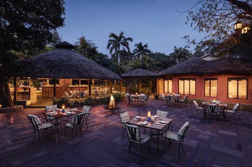 eine Terrasse mit Tischen und Stühlen vor einem Gebäude in der Unterkunft Taj Corbett Resort and Spa Uttarakhand in Rāmnagar