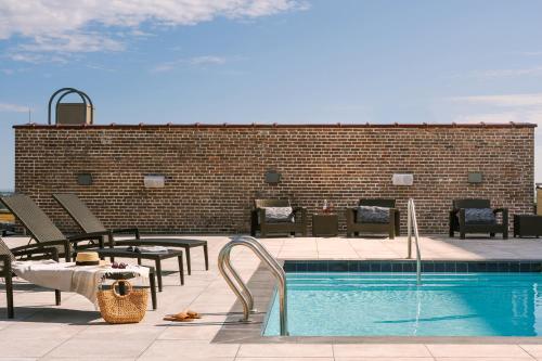 uma piscina com mesas e cadeiras ao lado de uma parede de tijolos em Sonder at 1500 Canal em Nova Orleans