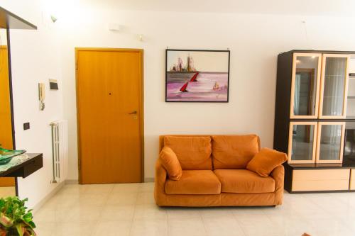 un divano arancione in una stanza con porta di Casa Ritella - ApulianStay Group a Monopoli