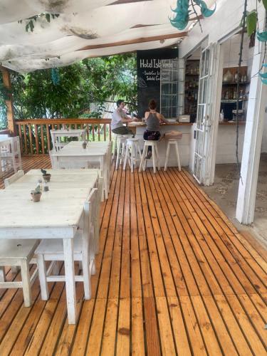 a patio with white tables and chairs on a wooden deck at La Bonita at Los Elementos in Santa Cruz La Laguna