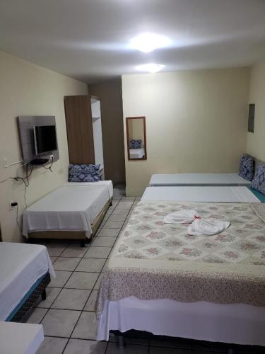 a hotel room with two beds and a tv at Pousada Jasmine in João Pessoa