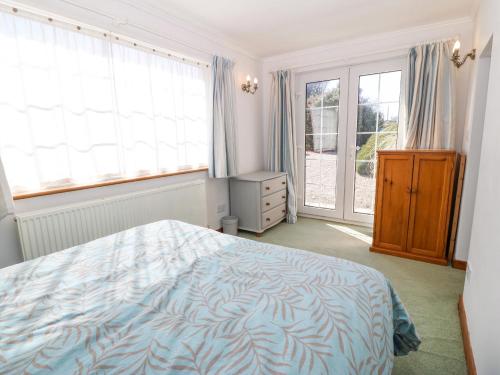 una camera da letto con un letto con un piumone blu e finestre di Llwyn Celyn a Pwllheli