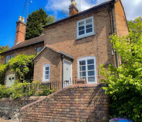 a brick house with a white door on a brick wall at Carrow Cottage in Ironbridge