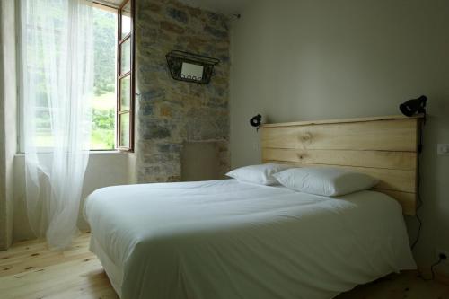 a bedroom with a white bed with a brick wall at Hôtel-Restaurant Le Parisien in Les Vignes
