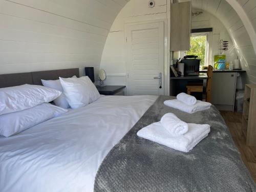 Una cama blanca con dos toallas encima. en Glamping Pod with ensuite WC Near Kingsbridge & Salcombe, en Kingsbridge