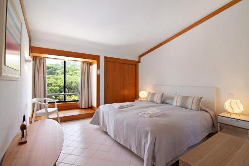 ein Schlafzimmer mit einem großen weißen Bett und einem Fenster in der Unterkunft Moradia V 60 in Quinta do Lago