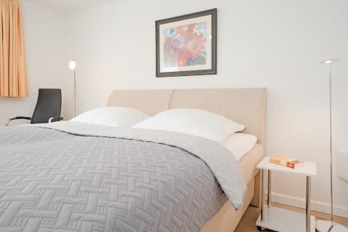a white bedroom with a bed with white pillows at Haus Eva Mar am Meer Appartement 5 in Timmendorfer Strand