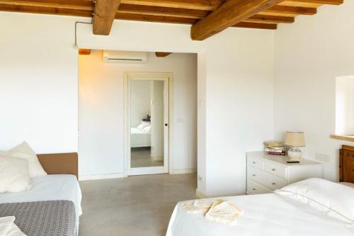 a white bedroom with two beds and a mirror at Villa meraviglia in Collazzone