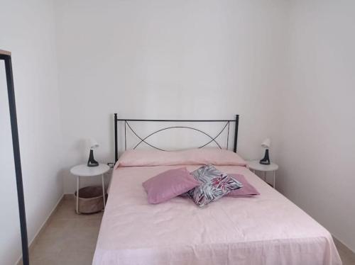 um quarto com uma cama com lençóis cor-de-rosa e duas mesas em Casa N.2 + piscina e palestra [1O km da Gallipoli] em Tuglie
