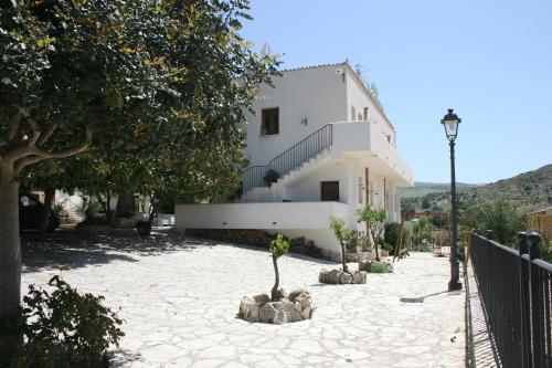 a white house with a courtyard with trees and a building at Hotel Il Cortile in Custonaci