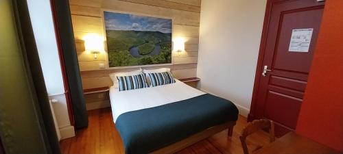 a small bed in a room with a painting on the wall at Logis hôtels Auberge du Château in Saint-Rémy-de-Blot