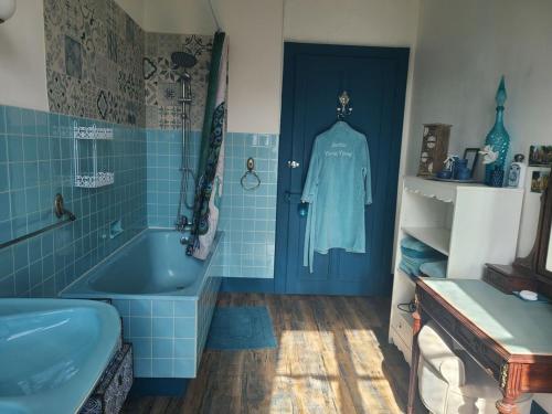 une salle de bain bleue avec une baignoire bleue et un lavabo dans l'établissement Chambre cosy avec accueil chaleureux, proche de Vittel et Contrexéville - FR-1-589-480, à Médonville