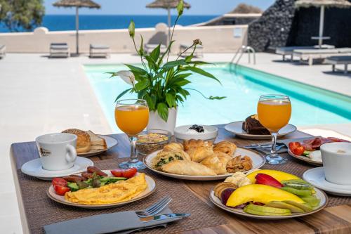 a table with plates of food and drinks next to a pool at En Plo Boutique Suites Oia Santorini in Oia