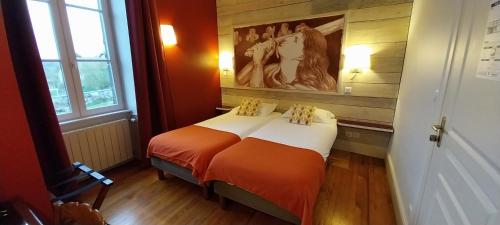 a bed in a room with a painting on the wall at Logis hôtels Auberge du Château in Saint-Rémy-de-Blot