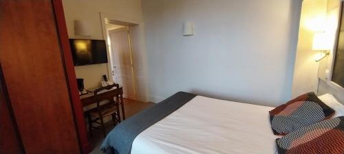 a bedroom with a bed and a desk in a room at Logis hôtels Auberge du Château in Saint-Rémy-de-Blot