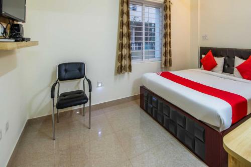 a bedroom with a bed and a chair in it at Hotel O Sagar Comforts in Bengaluru