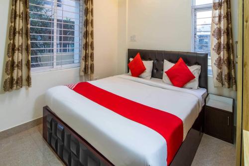 1 dormitorio con 1 cama grande con almohadas rojas en OYO Flagship 69694 Sagar Comforts, en Yelahanka