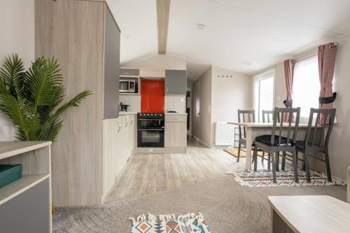a kitchen and living room with a table and chairs at Borwick Lakes Holiday Caravan (Partial Lake View) in Borwick