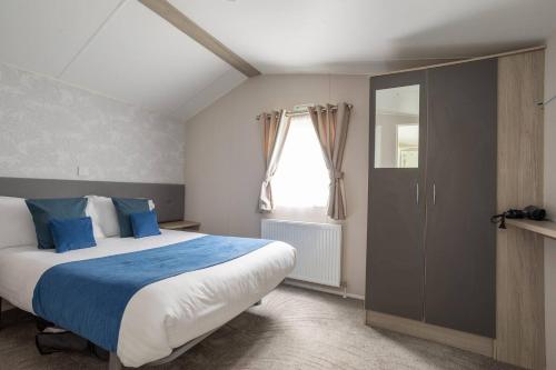 a bedroom with a large bed and a window at Borwick Lakes Holiday Caravan (Partial Lake View) in Borwick