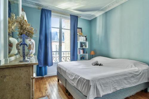 une chambre avec un lit aux murs bleus et une fenêtre dans l'établissement Appartement Chernoviz - Welkeys, à Paris