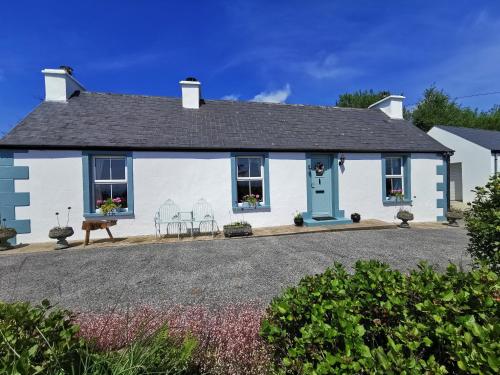 a white house with a blue door and chairs at New Listing - Ladybird Cottage - Donegal - Wild Atlantic Way in Donegal