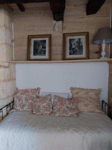 une chambre avec un lit avec deux tableaux au mur dans l'établissement 7 Au Charme d'Antan, à Beaumont-du-Périgord
