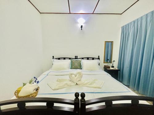 a bedroom with a large bed with white sheets and a bow at Sea Breeze Guest House in Negombo