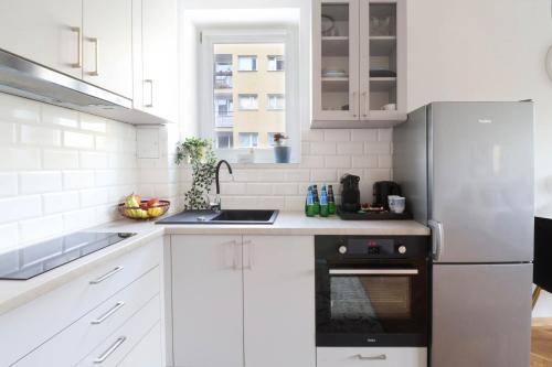cocina con armarios blancos y nevera en Apartments Vistula River by Arrenda, en Varsovia