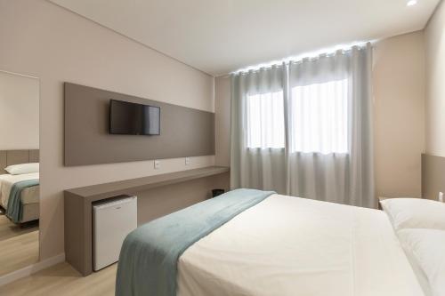 a bedroom with a bed and a tv on a wall at Tri Hotel Executive Osório in Osório