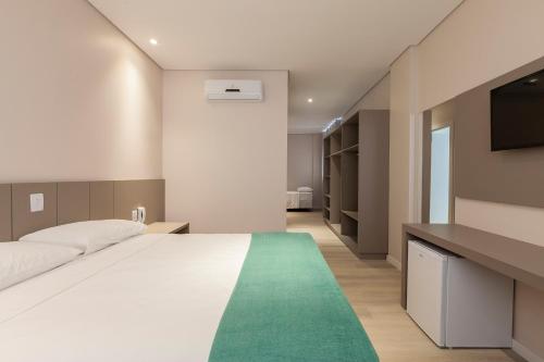 a bedroom with a large white bed with a green rug at Tri Hotel Executive Osório in Osório