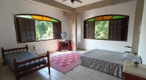 1 dormitorio con 1 cama y 2 ventanas en Eco hostel 013, en São Vicente
