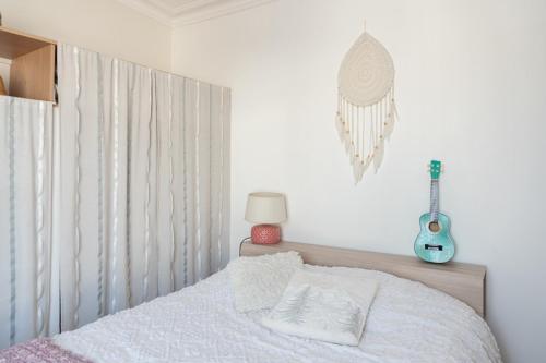 a bedroom with a bed with a guitar on the wall at Nice cocoon with garden near the Bois de Vincennes in Saint-Maurice