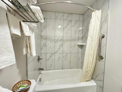 La salle de bains est pourvue d'une baignoire, d'un lavabo et d'une douche. dans l'établissement Llano Motel, à Llano