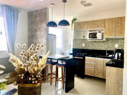 a kitchen with a black counter top and wooden cabinets at Hotel APART Zuccolotto 101 in Aracruz