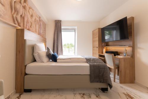 Schlafzimmer mit einem Bett, einem Schreibtisch und einem TV in der Unterkunft Hotel & Restaurant Sparta in Oldenburg