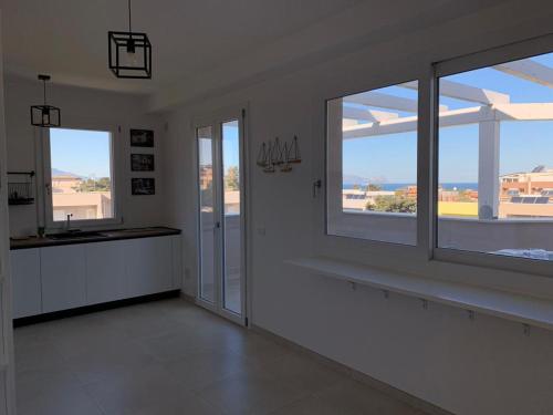 una camera bianca con due grandi finestre e una cucina di Terrace ini a Terrasini