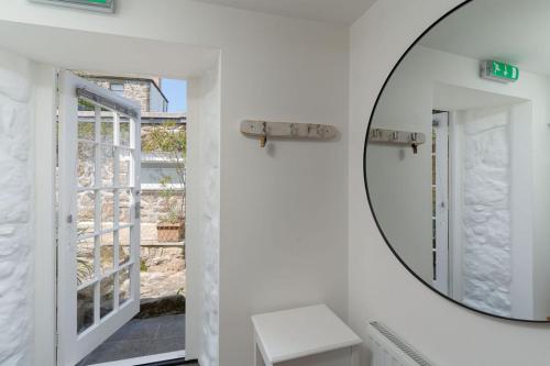 a mirror in a white bathroom with a window at The Old Pilchard Works in Mousehole