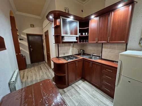 a kitchen with wooden cabinets and a sink and a refrigerator at One bedroom Apartment in the centre of Yerevan, Amiryan Street 5a in Yerevan