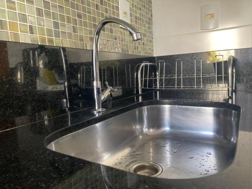 a stainless steel sink in a black tiled kitchen at Hotel APART Zuccolotto 101 in Aracruz