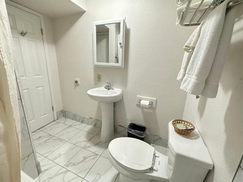 a white bathroom with a toilet and a sink at Llano Motel in Llano
