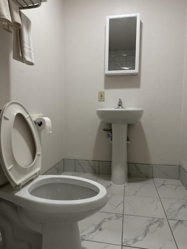 a white bathroom with a toilet and a sink at Llano Motel in Llano